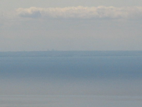 Die Sicht war ausgezeichnet. Man konnte vom Tower aus den Aussichtsturm und die Hochhaeuser von Niagara Falls sehen. Die Wegstrecke dorthin in fast einen Halbkreis ist so an die 150 km an der anderen Seite des Lake Orentario. Entschuldigung dafuer, die 12-fache Vergroesserung meiner Cam brachte nicht mehr, aber bei genauerem Hinsehen sind am Horizont tatsaechlich drei Erhebungen zu sehen!
