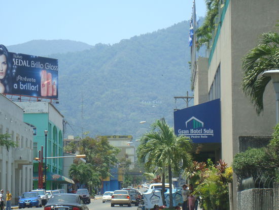 Im Hintergrund im Wald ein Riesenschriftzug des heiligen Getraenkes der Zentralamerikanischen Staaten (Coca Cola)