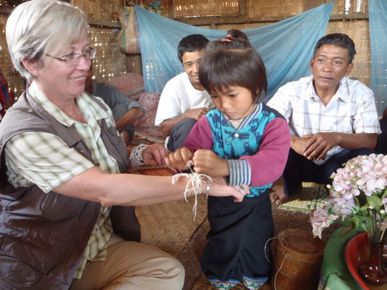 Kanya hat sich schick machen muessen (einen traditionellen Rock anziehen) und bindet mir hochkonzentriert das Baendchen um.