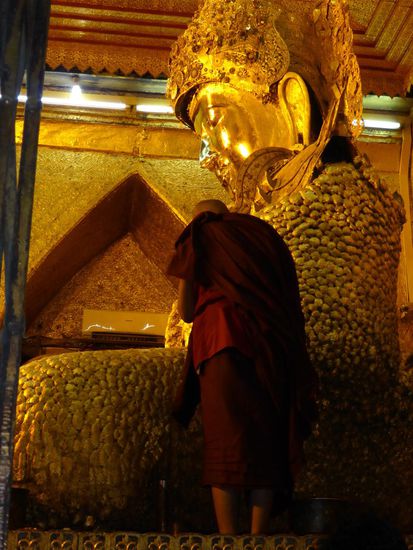 Der hochverehrte Buddha aus der Mahamundi Pagode (Mandalay) bekommt von einem Mönch weitere Golplättchen aufgeklebt.