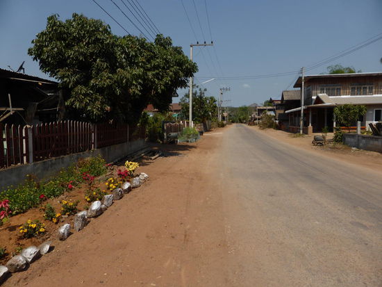 Dieses typische Straßen-Bild mit durchgängigen Holzhäusern, gepflegte Gärten und kein Mensch auf der Straße - findest du heute selten. Auch ganz typisch, diese rote staubige Erde.