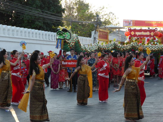 Straßenumzug mit tanzenden Schönen Frauen und im Hintergrund schon der nächste Drache!