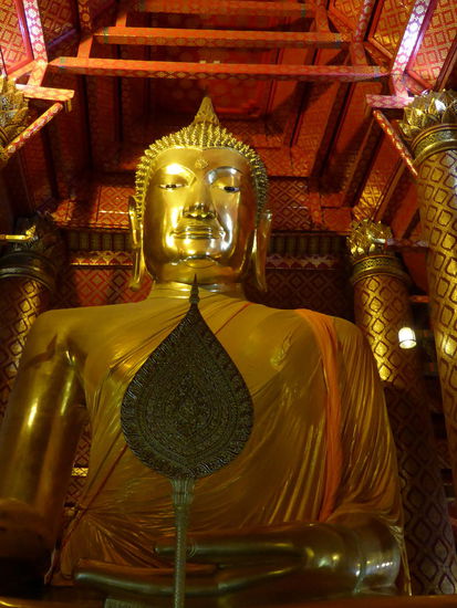 Der Buddha im Wat  Phanan Choeng ist riesengross und hoch verehrt. Ich bekomme kaum einen Platz auf dem Boden. Viele halten einen gelb orangen Umhang zum segnen hoch und es herrscht eine tiefe Stimmung.
Zum Buddha geht es durch einen großen Vorraum, in dem schon viele Statuen reich verziert und mit Goldplaettchen beklebt sind.