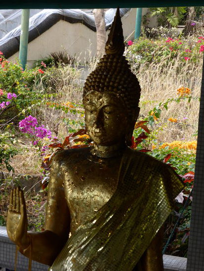 Buddha Kopf mit Goldplaettchen vor herrlicher Kulisse.