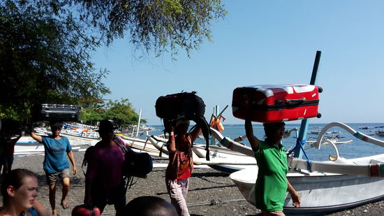 Die schweren Rucksäcke werden auf dem Kopf in das richtige Boot getragen.