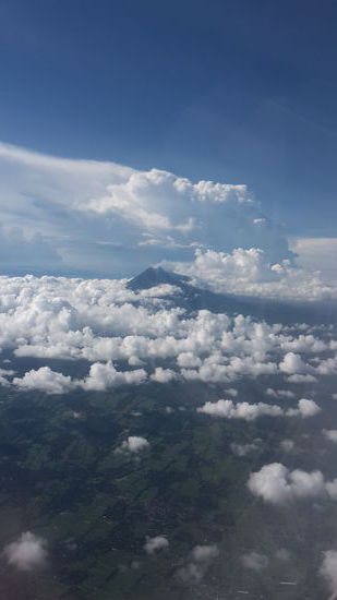 Die Anreise mit dem Flieger war gigantisch! Im Hintergrund ein aktiver Vulkan in Java. Wenn ich es richtig beobachtet habe, sind das nicht alles Wolken, an der linken Seite steigt Rauch auf.