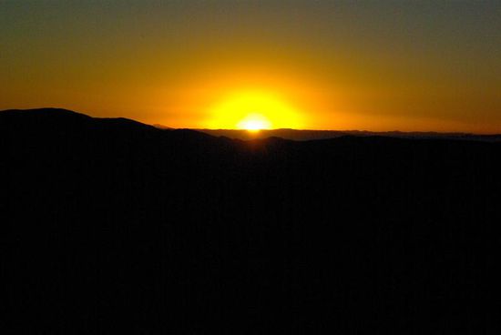 Man weiss gar nicht, wo man hinschauen soll. Auf der einen Seite geht die Sonne unter, und auf der anderen Seite faerben sich die Berge rot