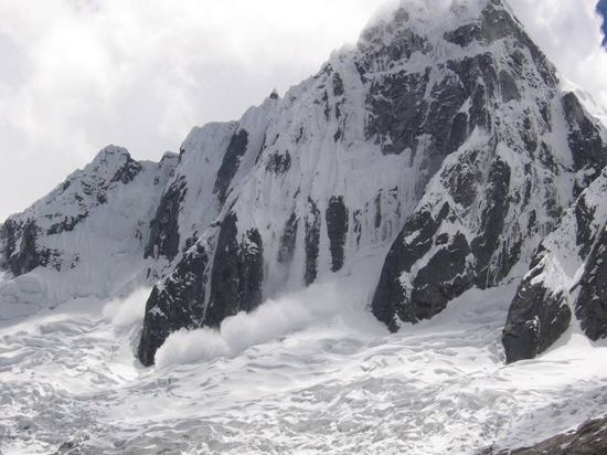 Eine Staublawine stuerzt den Taulliraju hinab