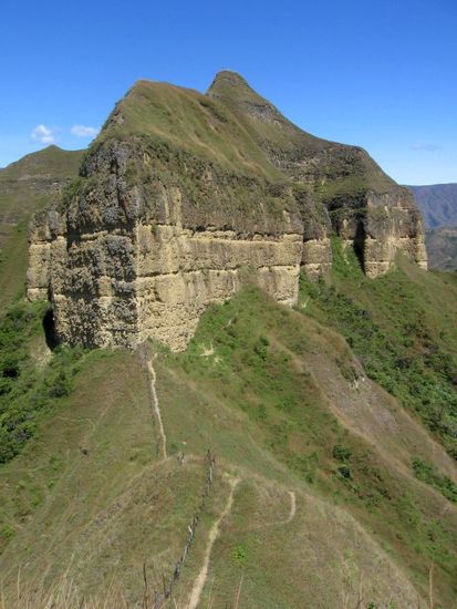 Blick vom ersten Kreuz zum Gipfel des Mandango mit dem zweiten Kreuz. Der Weg führt zuerst rechts an den Steilwänden vorbei und dann steil nach oben.