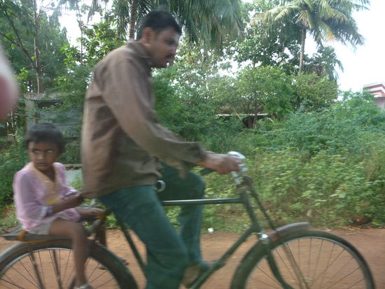 Sohn mit Vater auf dem Fahrrad unterwegs in Badami