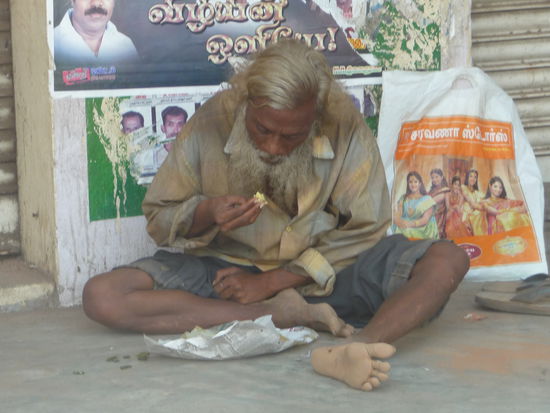 Inder nimmt seine Mahlzeit zu sich am Straßenrand in Ponchi