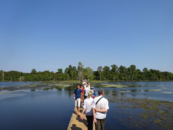 Über einen langen Holzsteg geht es über den See zum Neak Pean Tempelturm in Angkor