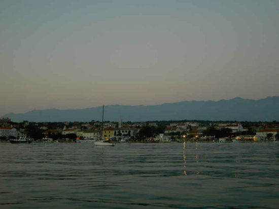 Novalija in der Abenddämmerung.
Das Gebirge im Hintergrund ist schon das Festland, das Velebit-Gebirge
