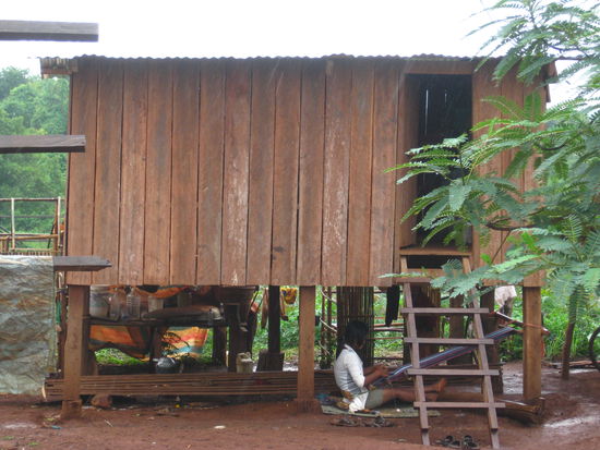 Ein junges Mädchen das vor dem regen geschützt unter dem Haus webt