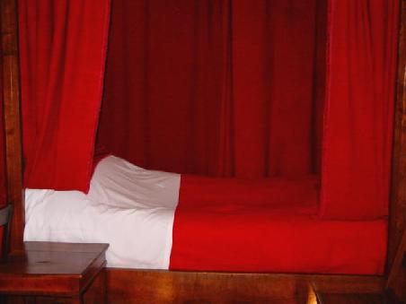 Hôtel-Dieu in Beaune, Armensaal; hinter dem Vorhang auf der Rückseite des Bettes befand sich ein schmaler Gang als Zugang für Arzt und Schwestern. Darin befand sich pro Bett eine Holztruhe für die Aufbewahrung der persönlichen Habseligkeiten der Kranken.