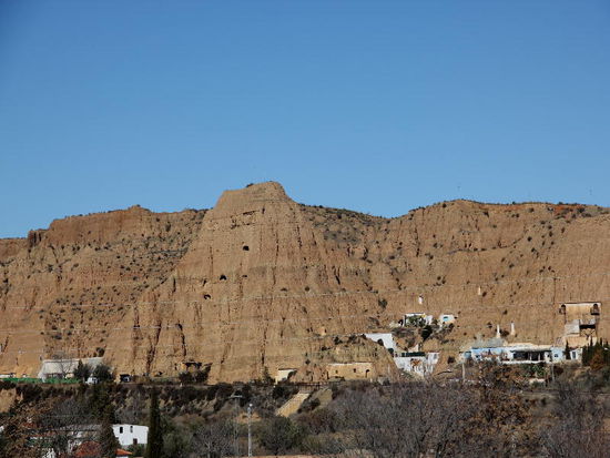 Felsenwohnungen in Guadix (beachte die Kamine im Fels oberhalb der Siedlung...)