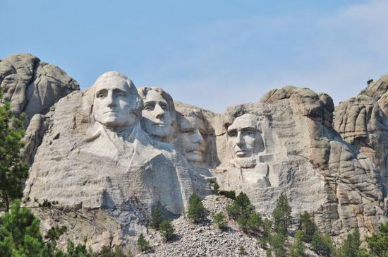 Die über 20 m hohen Köpfe der 4 Präsidenten Washington, Jefferson, Lincoln und T. Roosevelt beim Mount Rushmore - für Amerikaner fast ein Muss, diese Stätte mal besucht zu haben...; über Sinn und Zweck eines derartigen Monuments im ehemals sakrosankten Sioux-Gebiet wird sich wohl kaum jemand hinterfragen...
An einem andern Berg wird derzeit an einer weiteren Riesenskulptur gearbeitet, am Denkmal des Sioux-Häuptlings Crazy Horse - als Erinnerung an die Vertreibung der Indianer...