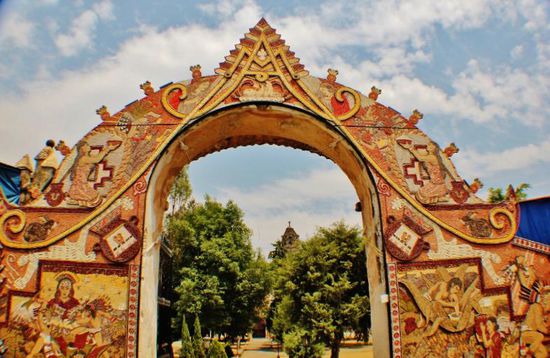 Der gewölbte Eingang zum Kloster Dominico de la Natividad ist mit einem aufwendigen Wandgemälde aus Samen und Körnern geschmückt, das Themen und Symbole der vorspanischen Geschichte darstellt...