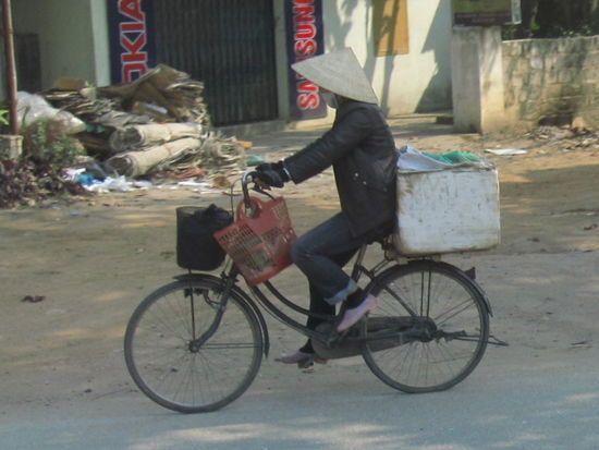 mit dem typischen vietnamesichem Hut und dem Mundschutz auf den Strassen in Vietnam
