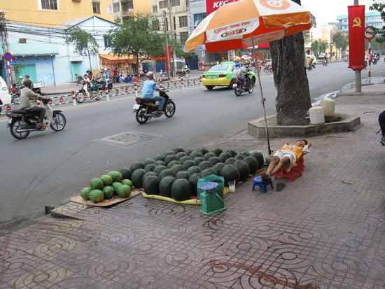 Strassenleben in Saigon...ein kleiner Junge verkauft Melonen und schlaeft dabei 