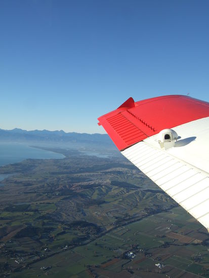 Die Ausblick war absolut atemberaubend, ich konnte weit uebers Meer blicken und in der Ferne sogar den Mount Taranaki, einem hohen Berg der Nordinsel, sehen.
In der kleinen Klapperkiste gab es natuerlich keine Sitze, es ist eng und laut.
Ich war als erster mit dem Sprung dran.
Man springt ja nicht allein, sondern im Tandem.
Ich war also fest vor dem Bauch meines Sprunglehrers geschnallt; dann ging die Tuer auf und wir sind zusammen an die Kante gerutscht.
Ich musste dann schon ganz aus dem Flieger raus und hing praktisch in der Luft und dann:
SPRUNG
Die ersten Sekunden sind unglaublich, ploetzlich jagt man baeuchlings, die Arme weit ausgestreckt in einem Wahnsinnstempo der Erde entgegen!
Meine Freudensschreie waren sicher ohrenbetaeubend.