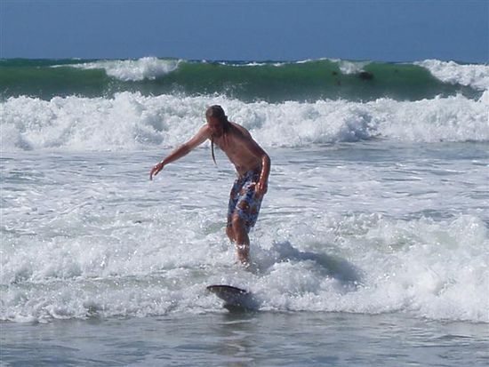Das Surfbrett (mein Woodie) und ich. Es ist nicht das beste Photo, denn da bin ich schon sehr dicht am Strand und somit kurz vor Ende!
Aber im Hintergrund seht ihr ja die Wellen. Man faengt halt bei der grossen Welle an und laesst sich dann geradeaus Richtung Strand pushen. Mittlerweile gelingt es mir die grossen Wellen zu catchen und schraeg zu reiten!