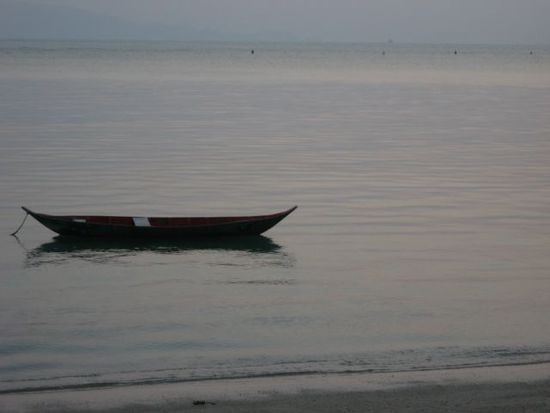 Im Wasser stehende Fischer draußen im seichten Meer (siehe die schwarzen Punkte am am Horizont)