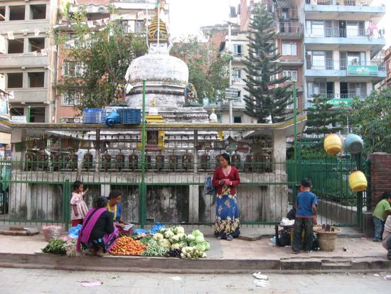 Gemueseverkauf, im Hintergrund ein Stupa mit Gebetsmuehlen