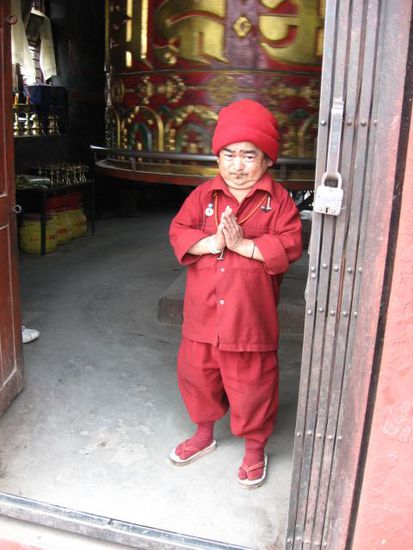 kleiner Mann vor grosser Gebetsmuehle in Boudhanath-Stupa