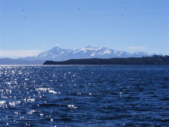 Das saphirblaue Wasser des Lago Titicaca und im Hintergrund schneebedeckte Andengipfel.