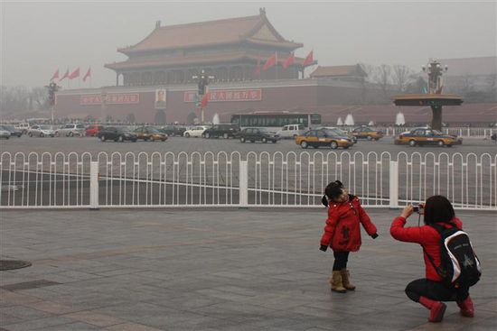 Ein kleines Mädchen posiert für ihre Mama vor dem Tiananmen Square. Wie man sieht, sieht man kaum etwas wegen der starken Luftverschmutzung. Die andere Straßenseite ist gerade so zu erkennen.