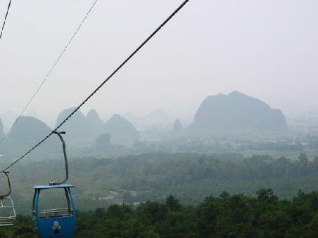 Blick ueber Guilin bei der Gondelfahrt auf den Berg Yao, ueberall ragen die Karstberge auf
Vue sur Guilin et ses environs depuis la montagne Yao.