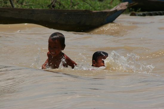Froehliche Kinder toben in den Wellen
