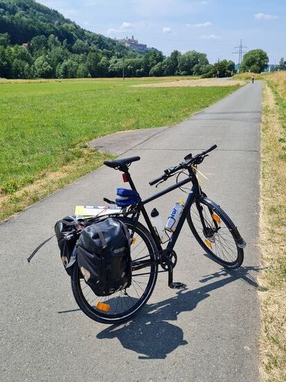 Geht man von der Sattelmiite nach oben, erscheint in der Ferne auf der Anhöhe die Silhouette eines Wahrzeichens einer sich nähernden Stadt.