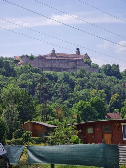 Es handelt sich um die Plassenburg, hoch über der bestbekannten Bierstadt Kulmbach thronend.
Die Plasenburg ist ein ehemaliges Residenzschloss in Oberfranken, entstanden um 1135 als sogenannte "Höhenburg".
Zwischenzeitlich in 1554 zerstört, wurde sie später als imposante Festung und großes Schloss im Renaissancestil wieder aufgebaut.
Als 1810 Kulmbach an Bayern fiel, wurde die Burg in der Folgezeit als Zwangsarbeiterhaus, Zuchthaus und Kriegsgefangenenlager verwendet.
Ab 1929 begann dann die museale Nutzung und mittlerweile sind vier Museen Bestandteil dieer Burg.
Von Kulmbach selbst ist eine Kleinsiedlung aus der Zeit um 900 n. Chr. bekannt.
Der Name Kulmbach stammt vom Begriff "kulma" ab, der zwischen 1028 und 1040 in einer Schenkungsurkunde erwähnt wurde.