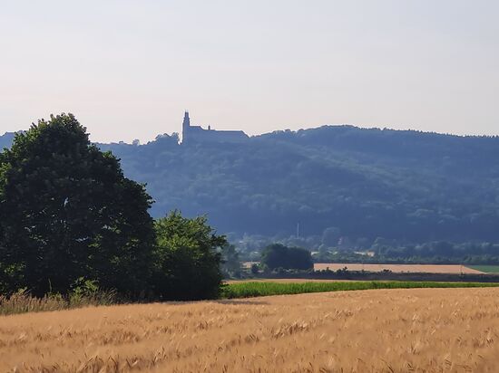 Jetzt wieder (fast) zu Tale, etwa 100 hm (Höhenmeter) tiefer als die visitierte Basilika Vierzehnheiligen, erscheint wieder eine auffällige Immobilie, allerdings auf der Anhöhe der anderen Seite des Maintals und noch dazu bei ungünstigen Lichtverhältnissen. Die Auflösung des Rätsels folgt bald am Anfang des zweiten Tages.
