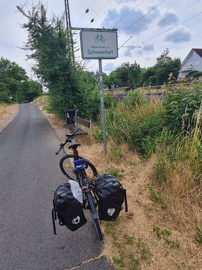 Gut 25 km nach Haßfurt werde ich gegen 16:30 Uhr von einer Tafel freundlich am Eingang von Schweinfurt empfangen. In der Stadt selbst will ich nicht nur wegen der relativ frühen Tageszeit die heutige Fahrt beenden. 
So radle ich noch ein kurzes Stück weiter, um an der Mainlände eine Rollpause einzulegen und da ich auch noch keine Unterkunft für den heutigen Tag hatte, startete ich per Handy-Internet die Quartiersuche mainabwärts nach Schweinfurt.