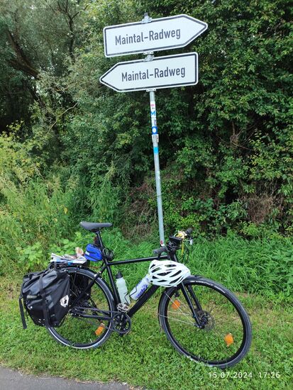 Ja, ich befinde mich noch auf dem richtigen Radweg und strebe rechterhand weiter.
Am Gepäckträger ist übrigens seit dem morgendlichen Start zu Hause noch der
"Mangfall-Bote", meine heimatliche Tageszeitung eingeklemmt. Zum Lesen hatte ich wie üblich auch während der Anreise mit dem Zug kaum Zeit vor lauter aus dem Fenster gucken...