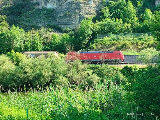 Einwurf für (Hobby-)Eisenbahner: Schwer zu erkennen (am schärferen Originalfoto ist das entscheidende Detail noch besser zu sehen) zieht eine DB Güterzuglok der Baureihe 185 (TRAXX 2 vom Hersteller Bombardier) mit einer Leistung von 5600 kW
Dauerleistung einen sog. "Mischer" oder auch "Gemischtwarenladen" (Güterzug mit unterschiedlichen Güterwagengattungen) in Richtung Würzburg und weiter.
