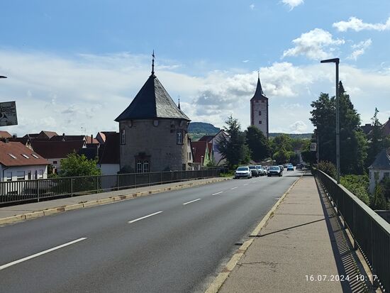 Blick zur rechten Seite Karlstadts:
Der direkt an der Mainbrücke gelegene Mühlturm aus dem 13.-15. Jahrhundert mit dem charakteristischen Zeltdach ist Bestandteil der Stadtmauer. Er war früher ein Lochgefängnis und bekam in der zweiten Hälfte des 19. Jahrhunderts einen neugotischen Ausbau.
Im Hintergrund der Katzenturm von ca. 1350 ist einer von früher 24 Stadttürmen und wurde 1990/91 renoviert, kann aber angeblich nicht bestiegen werden.