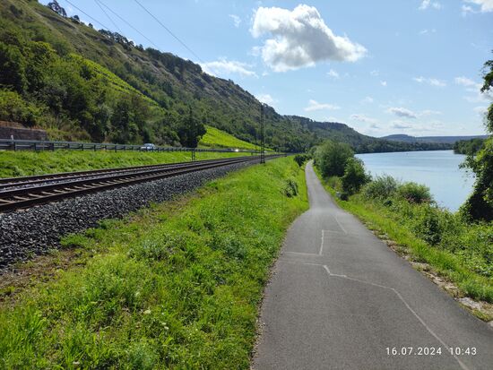 Ein weiterer Blick zurück, nachdem ich die kurze Steigung vor mir "souverän" absolviert hatte:
Vier parallele Verkehrsmagistralen im Maintal in Form der B26 ganz links hinter der Leitplanke, dann die Maintalbahn, rechts die Bundeswasserstraße Main und zwischen Bahn und Main der Genussradler-Highway entlang des Mains.
Schade, daß gerade abgesehen von einem Kfz, weder Zug, Schiff und auch keine weitereren  Radler zu sehen sind - "Magistralenflaute"