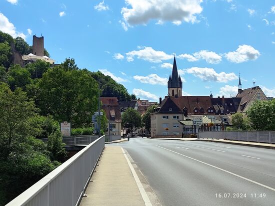 Rückblick von der Fränkischen Saalebrücke auf das Ortszentrum der Stadt Gemünden am Main.
Gemünden mit seinen 10.000 Einwohnern liegt auf 160 m Höhe und etwa 40 km mainabwärts von Würzburg.
Man kann zur Lage auch sagen:
Am linken oberen Ende des Maindreiecks, wo der Main kurz seine Richtung zum rechten oberen Beginn des Mainvierecks bei Lohr am Main ändert, um dort wiederum seine Fließrichtung zu ändern und zwar für längere Zeit in Richtung Süden.
Erstmals urkundlich erwähnt wurde der Ort in 1243, allerdings wird eine bereits frühere Stadterhebung vermutet.
Links oben die Ruine Scherenburg, auch mit Schloss Scherenberg betitelt.