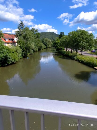 Direkt am Übergang zwischen Gemünden am Main und Kleingemünden geht der Blick von der Saalebrücke an der Fränkischen Saale hoch, die sich aus leicht nordöstlicher Richtung das letzte kurze Stück bis zur Mündung in den Main nähert. Etwa 140 km war sie vom Quellgebiet bei Bad Königshofen, ca. 10 km nördlich von Haßfurt und gut 5 km westlich der Landesgrenze zu Thüringen, unterwegs.
Etwas oberhalb der Bildmitte mündet hier nicht sichtbar die Sinn aus dem Sinntal in die Fränkische Saale, weswegen Gemünden auch in Bezug auf Passau als 
"fränkische Dreiflüssestadt" benannt wird.