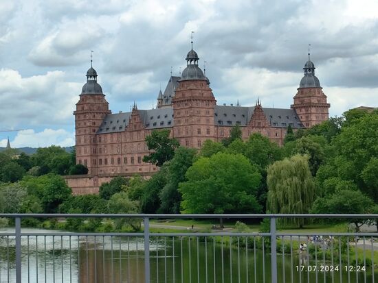 Von der Willigisbrücke aus erblickt man Schloß Johannisburg.
Die Vierflügelanlage wurde zwischen 1605 und 1614 errichtet, nach dem 
2. Weltkrieg bis 1964 wieder instandgesetzt und beinhaltet seit 1972 Teile der Städtischen Sammlungen. Unterhalb des Schlosses sieht man am rechten Mainufer den weiteren Verlauf des Mainradwegs als schmalen grauen Streifen.