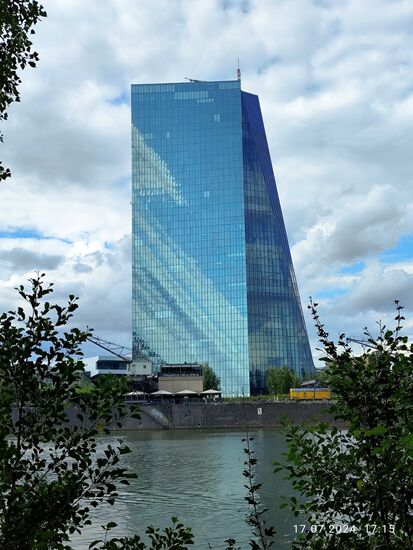 Als erstes Hochhaus tritt am gegenüberliegenden Mainufer der EZB-Tower in Erscheinung, seit 2014 die neue Hauptzentrale der Europäischen Zentralbank.
Incl. der aufgesetzten Spitze erreicht er eine Höhe von 201 m.
Der Tower hat keine privaten Eigentümer, sondern gehört rein den Zentralbanken, um nicht von privaten finanziellen Interessen beeinträchtigt werden zu können.
Für mich allerdings ist das absolute Highlight dieses Bildes das gelbe Objekt rechts vor dem Tower.
