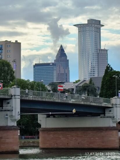 Im Hintergrund der Messeturm mit seinem charakteristischen Spitzdach ("Bleistift") mit 256,5 m Höhe das zweithöchste Hochhaus in der EU.
Rechts davon der Westend Tower oder auch Kronenhochhaus mit 208 m Höhe auf 53 Obergeschosse. Wurde 1993 fertiggestellt und ist Sitz der DZ-Bank.