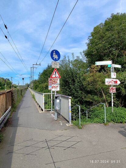 Zur linken Seite beginnt rechts an der Bahnstrecke in Richtung Mainz der Fußgänger- und Radlersteg an der Vorlandbrücke, der dann an der Stahlkonstruktion der Strombrücke der "Südbrücke Mainz" über den Rhein seine Fortsetzung findet. Dazu später noch mehr.
