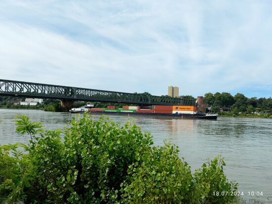 Ein Containerschiff schiebt sich rheinabwärts unter der Südbrücke hindurch.