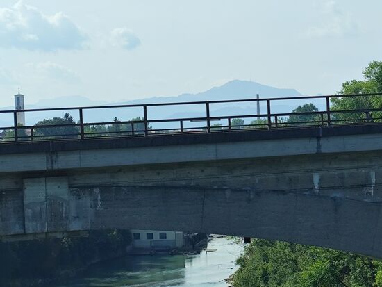 Der große Bergrücken im Hintergrund ist der Grünten, aufgrund seiner auffälligen Lage am Alpenrand auch "Wächter des Allgäus" genannt.
Der (Bergrücken) Grünten besteht aus dem Hauptgipfel "Übelhorn" (1738 m) und 6 weiteren Nebengipfeln. Des weiteren kann man bei Fotovergrößerung etwas rechts und etwas tiefer wirkend schemenhaft die große Sendeanlage des
Bayrischen Rundfunks wahrnehmen.
Während hier auf dem Foto ein letzter Teil der aus Richtung Oberstdorf zufließenden Iller erkennbar ist, der Hinweis, daß ich in 2022 die Iller von Oberstdorf bis zur Mündung in die Donau gleich westlich von Ulm und in 2021 die Wertach bis zur Mündung in den Lech im Norden Augsburgs beradelt habe, diese Touren allerdings erst zu einem späteren Zeitpunkt, aber dann hoffentlich doch noch vor der geplanten 2026er-Tour zur Veröffentlichung kommen.