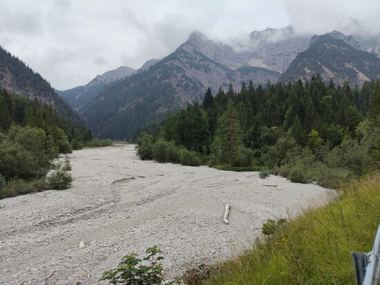 Ein momentan ausgetrocknetes, geweitetes Bergbachbett, das aus südlicher Richtung ankommt. In meiner Fahrtrichtung hier nach links wird dann bald Schloß Linderhof erscheinen.